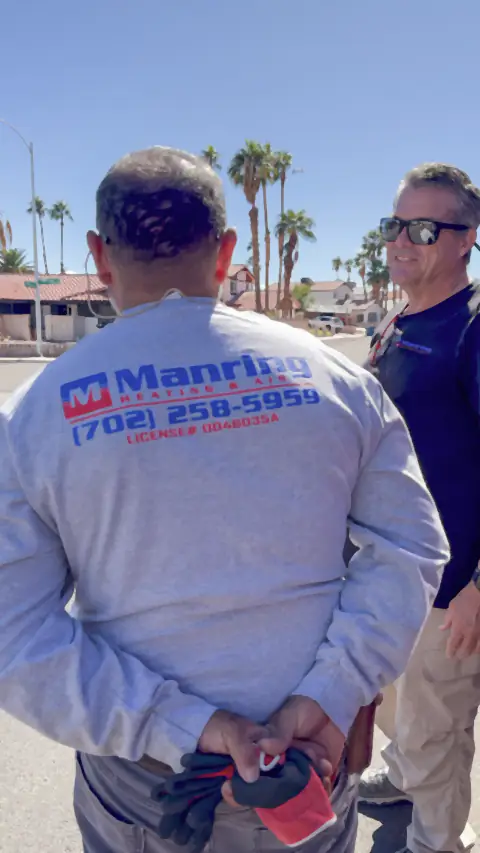 Two men on site, one in a Manring Heating & Air shirt showing the company phone number