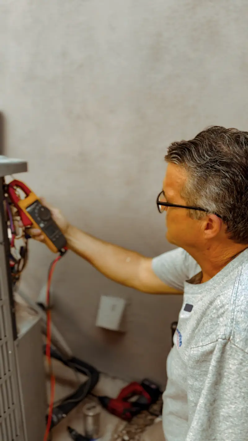 Manring technician testing the wiring of an HVAC unit with a clamp meter